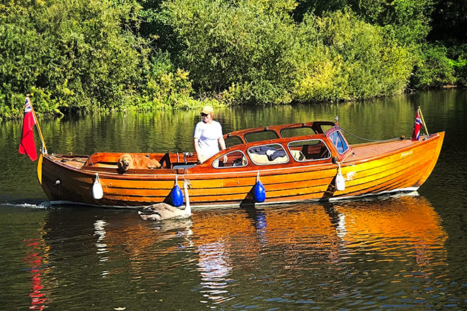 Happy dog and owner driving their boat back to her Henley mooring.