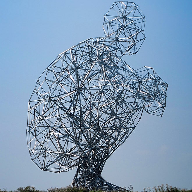 This gigantic artwork of large steel; a squatting man sitting at the dyke of the Markermeer lake created by Antony Gormley is called 'Exposure'.