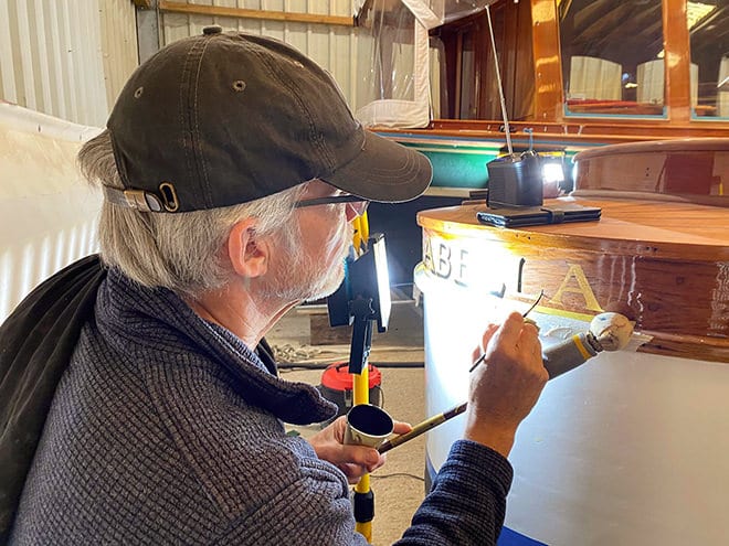 Tim Bird gilding the signwriting on 'Arabella'