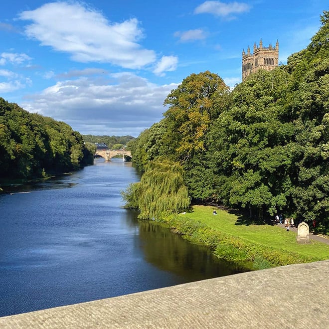 Durham cathedral peeking above the trees on the banks of the river Wear.