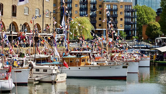 A celebration of heritage craft, polished brightwork and fluttering signal flags against the backdrop of St Katharine Docks.